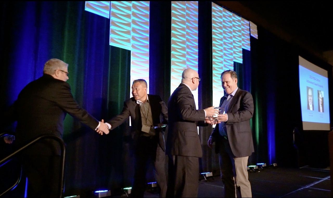Executives shaking hands during an awards presentation on stage