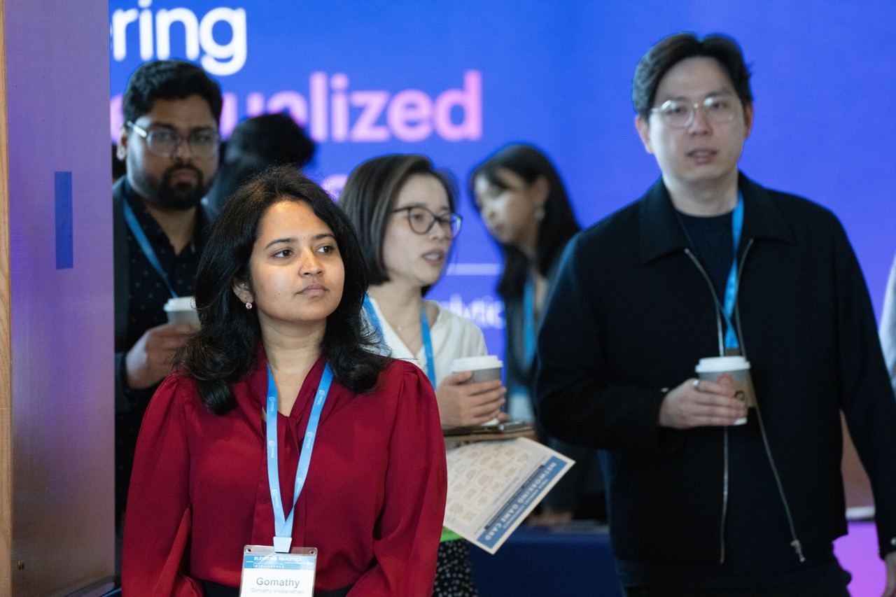 Conference attendees arriving at a session with coffee and lanyards