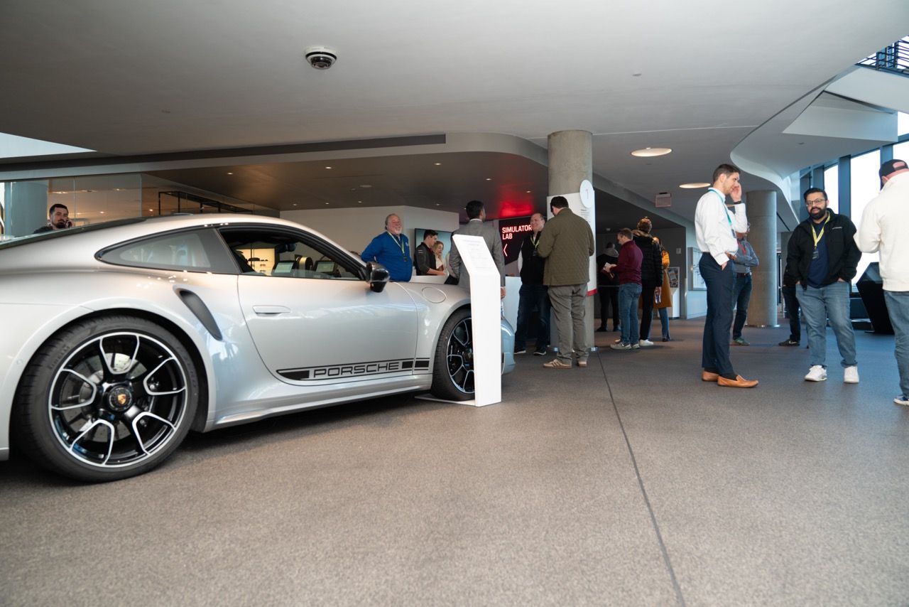 Guests mingling beside a sports car in a showroom lounge