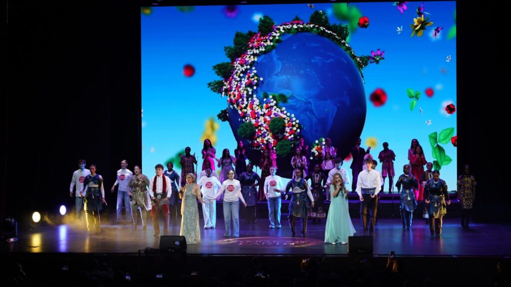 Full cast finale of Symphony of the Earth with a flower-covered globe on the LED screen