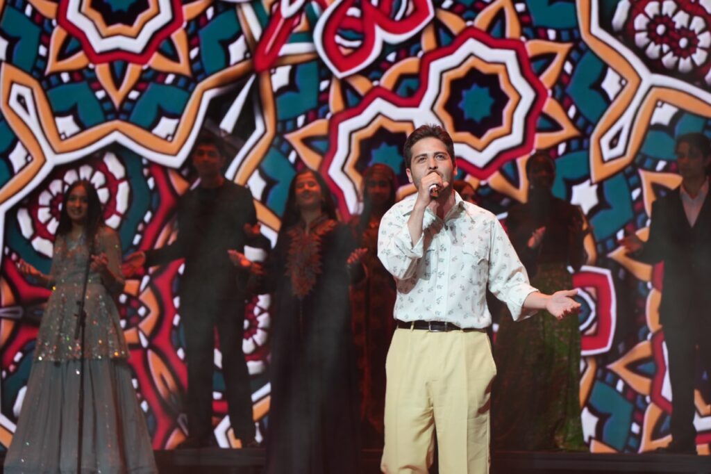 Singer performs in front of a colorful mandala pattern on the LED screen
